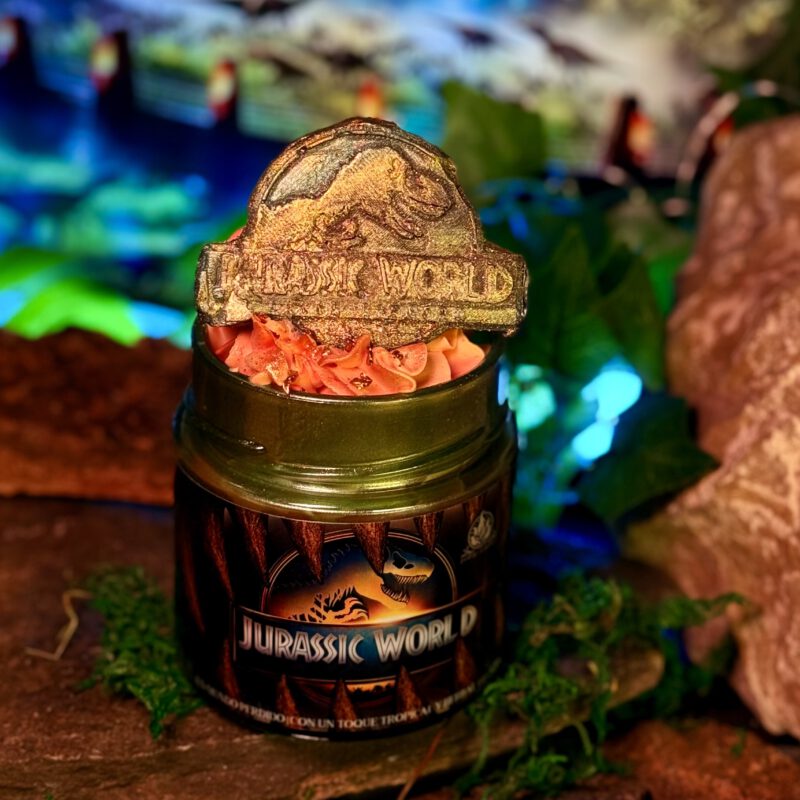 Vela decorativa de Jurassic World con dinosaurio de fondo, inspirada en la saga jurásica dirigida originalmente por Spielberg.