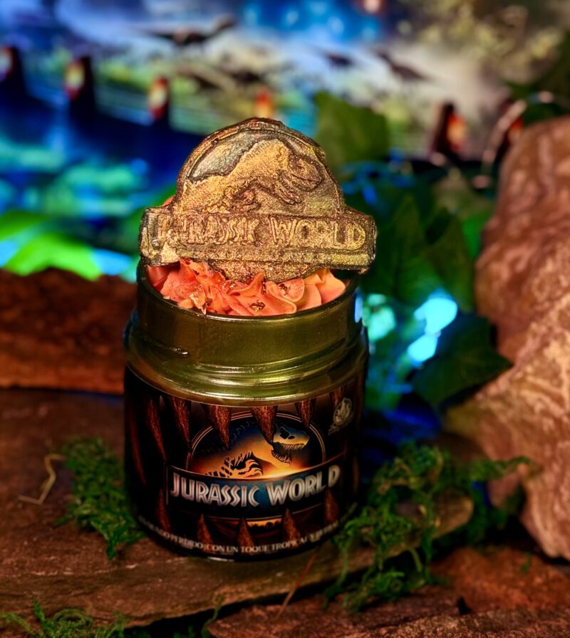 Vela decorativa de Jurassic World con dinosaurio de fondo, inspirada en la saga jurásica dirigida originalmente por Spielberg.