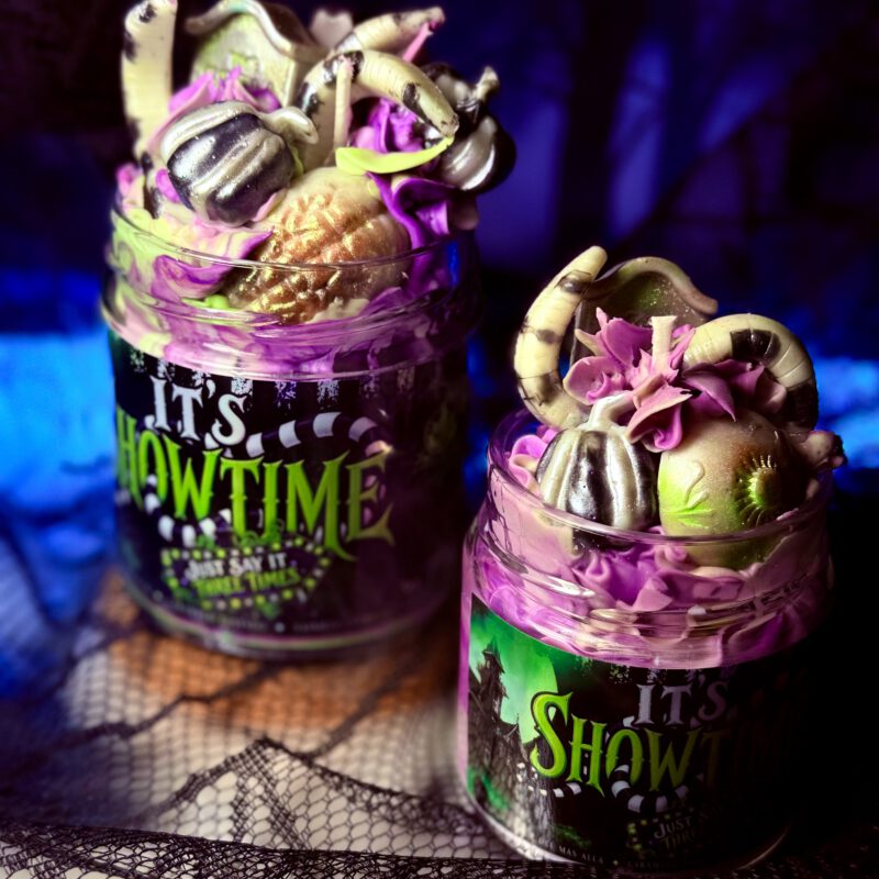 Vela It’s Showtime inspirada en Beetlejuice con decoración de cera en tonos verdes, rosas y morados.